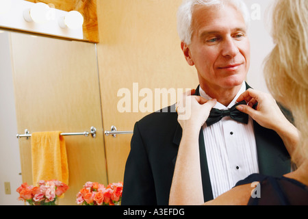 Vista posteriore di una donna matura regolando il filtro bow tie di un uomo maturo Foto Stock