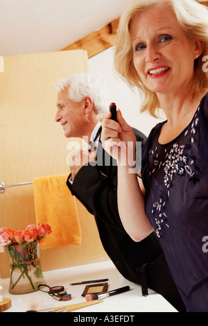 Ritratto di una donna matura tenendo un rossetto con un uomo maturo regolando il suo bow tie Foto Stock