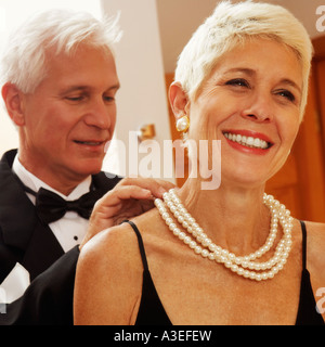 Close-up di un uomo maturo di mettere una collana di perle attorno a una donna matura il collo Foto Stock