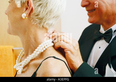 Close-up di un uomo maturo di mettere una collana di perle attorno a una donna matura il collo Foto Stock