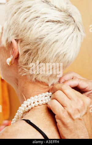 Close-up di un uomo maturo di mettere una collana di perle attorno a una donna matura il collo Foto Stock