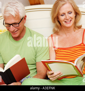 Close-up di una coppia matura seduta sul letto e la lettura di libri Foto Stock