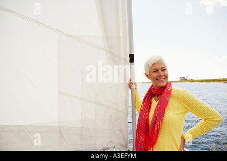 Donna matura in piedi in una barca a vela e sorridente Foto Stock