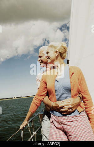 Uomo maturo abbracciando una donna matura da dietro in una barca a vela e sorridente Foto Stock