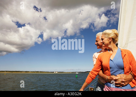 Uomo maturo abbracciando una donna matura da dietro in una barca a vela e sorridente Foto Stock