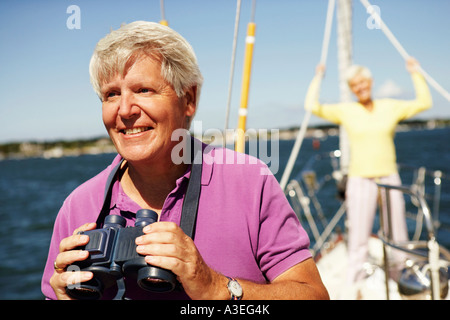 Close-up di un uomo maturo tenendo un binocolo in una barca con una donna matura dietro di lui Foto Stock