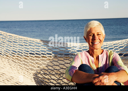 Ritratto di una donna matura seduta in una amaca e sorridente Foto Stock