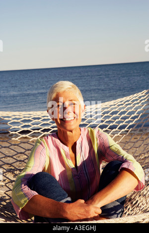 Ritratto di una donna matura seduta in una amaca e sorridente Foto Stock