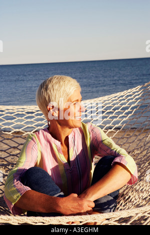 Close-up di una donna matura seduta in una amaca e sorridente Foto Stock
