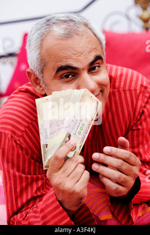 Ritratto di una metà uomo adulto che mostra la valuta indiana note Foto Stock