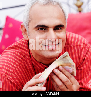 Ritratto di una metà uomo adulto tenendo la valuta indiana note e sorridente Foto Stock