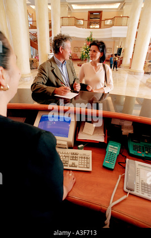 Controllo di coppia in hotel vista da dietro la scrivania Foto Stock