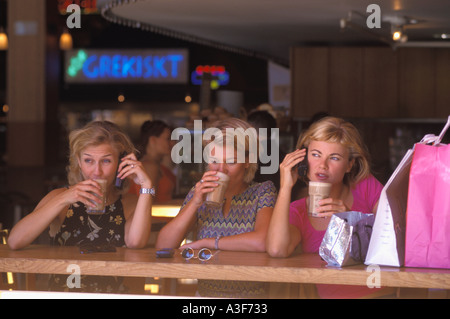 Tre donne svedesi in seduta marciapiede coffee house parlando su telefoni cellulari Foto Stock