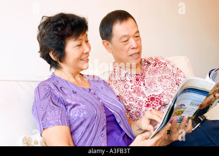 Close-up di un uomo anziano e una donna matura leggendo una rivista Foto Stock