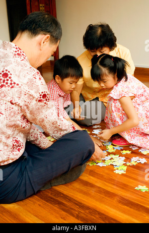 Ragazzo con una ragazza e i loro nonni giocare con un puzzle Foto Stock