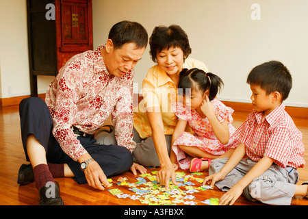 Ragazzo con una ragazza e i loro nonni giocare con un puzzle Foto Stock