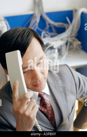 Close-up di un imprenditore in possesso di un ricevitore telefonico in una sala server Foto Stock