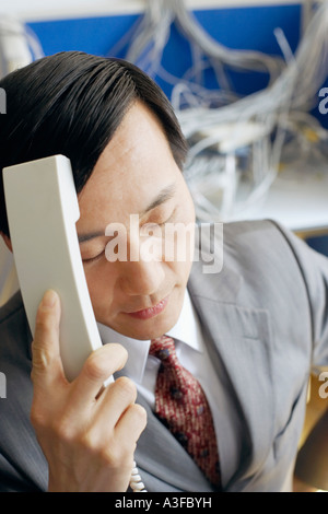 Close-up di un imprenditore in possesso di un ricevitore telefonico in una sala server Foto Stock