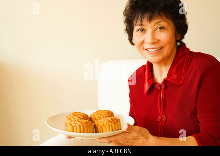 Ritratto di una donna matura tenendo una piastra di torte Foto Stock