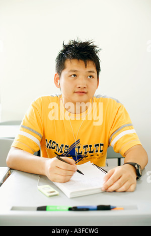 Giovane uomo seduto in aula e ascolto di un lettore MP3 Foto Stock