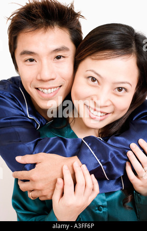 Ritratto di una metà uomo adulto abbracciando una giovane donna da dietro Foto Stock