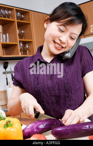 Close-up di una giovane donna di taglio di verdure e di parlare su un telefono cordless Foto Stock