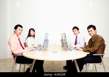 Ritratto di tre uomini di affari con una imprenditrice lavoro sui computer Foto Stock