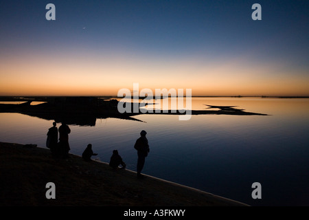 In tarda serata la luce che mostrano profili di persone il lavaggio nel fiume Niger e Mali Foto Stock