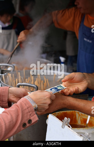 Una donna a pagamento in un giapponese sul mercato alimentare di viaggio in tempo reale momento di stock Foto Stock