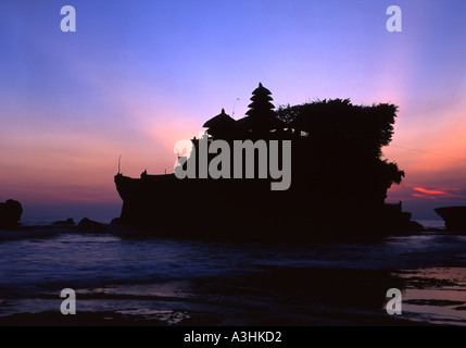 Alberi di luce da un bel tramonto appaiono da dietro la roccia e dal Tempio Tanah Lot Bali Indonesia Foto Stock