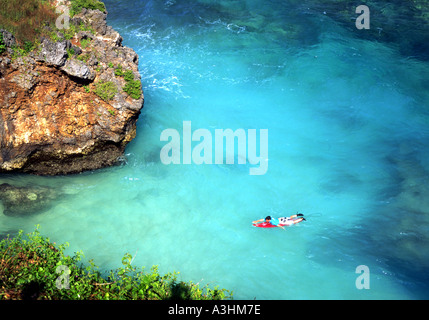 Un lone surfer paddling in acque incontaminate a ullawatu Bali Indonesia Foto Stock