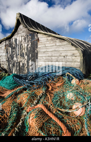 Capovolta la barca da pesca utilizzato come un capannone con la pesca e le reti al di fuori su di Isola Santa, Lindisfarne Foto Stock