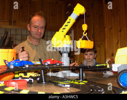 Uomo che gioca con il giocattolo del bambino, mentre il ragazzo guarda sopra. Mai crescere! Foto Stock