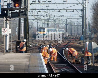 Linea ferroviaria diretta con gli addetti alla manutenzione in alta visibilità abbigliamento di sicurezza lavorando su via Foto Stock