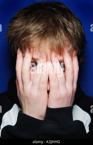 Ragazzo adolescente che copre il volto Foto Stock