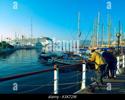 Gli uomini la pesca come la Costa Atlantica nave da crociera arriva a Marmaris Foto Stock