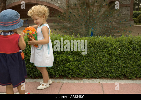 Due giovani ragazze alimentando un pavone in el Parque del Buen Retiro Madrid Spagna Europa Foto Stock