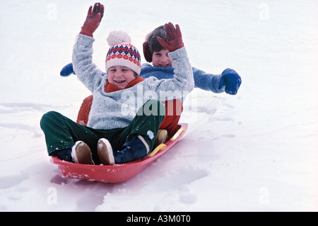 Ragazzi slittino sulla collina in inverno Foto Stock