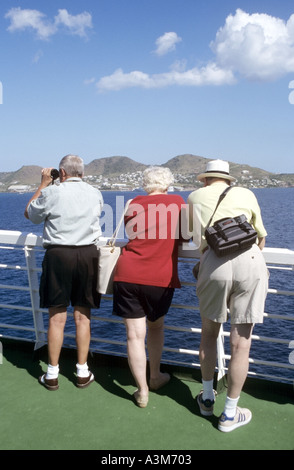 Basseterre Hills e il litorale vista posteriore di tre uomo maturo & donna su una nave da crociera guarda approccio camicia isola di Saint Kitts Nevis Caraibi orientali Foto Stock