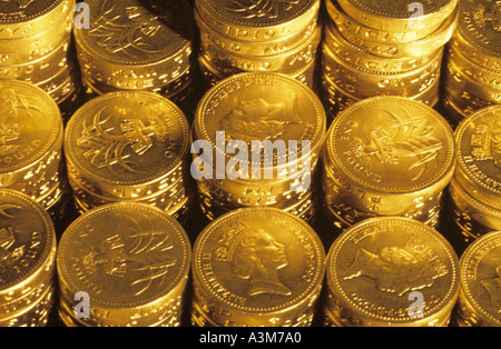 Close up di pile di denaro del Regno Unito una sterlina monete in contanti sotto illuminazione oro Concetto di immagine per nido uovo pila di risparmio di denaro di pile di denaro Foto Stock