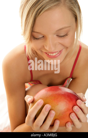 Giovane donna azienda mango Foto Stock