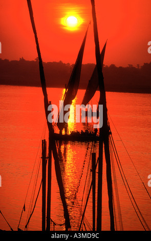 Feluche scivolano lungo il fiume Nilo in rosso tramonto Egitto Foto Stock