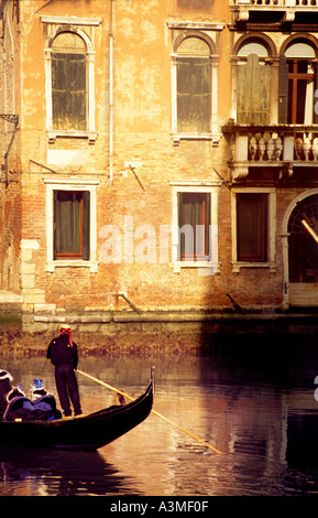 Luce calda del pomeriggio gondoliere in piedi sul retro della gondola di prendere i turisti in tutta calma canali Venezia Italia Europa Foto Stock