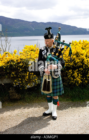 Lone Piper riproduzione di cornamuse in corrispondenza del bordo di Loch Ness in Scozia. Foto Stock