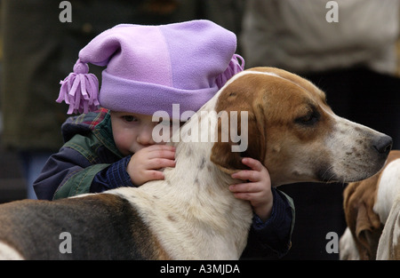 Bambino con strappo sulla guancia abbracci hound come Heythrop Hunt raccoglie in Stow on the Wold Foto Stock