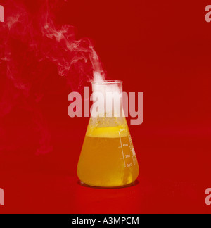 Il cloruro di ammonio di fumo matraccio di erlenmeyer liquido giallo contro bold sfondo rosso Foto Stock
