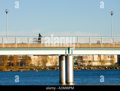 Ciclista godendo la vista da un ponte che attraversa il fiume Oulujoki Oulu FINLANDIA Foto Stock