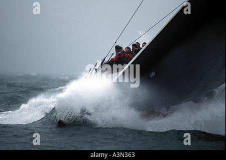 Prua di maxi yacht da regata crash Stealth attraverso un'onda in cattive condizioni Foto Stock
