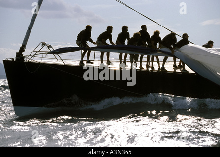 Equipaggio a bordo di una barca da regata di lotta per tirare lo spinnaker a bordo come si trascina in acqua Foto Stock