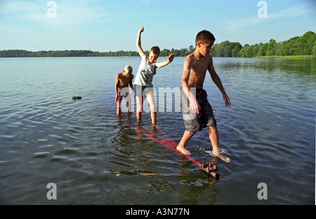 Ragazzi in equilibrio su una barra di traino nell'acqua, Lituania Foto Stock